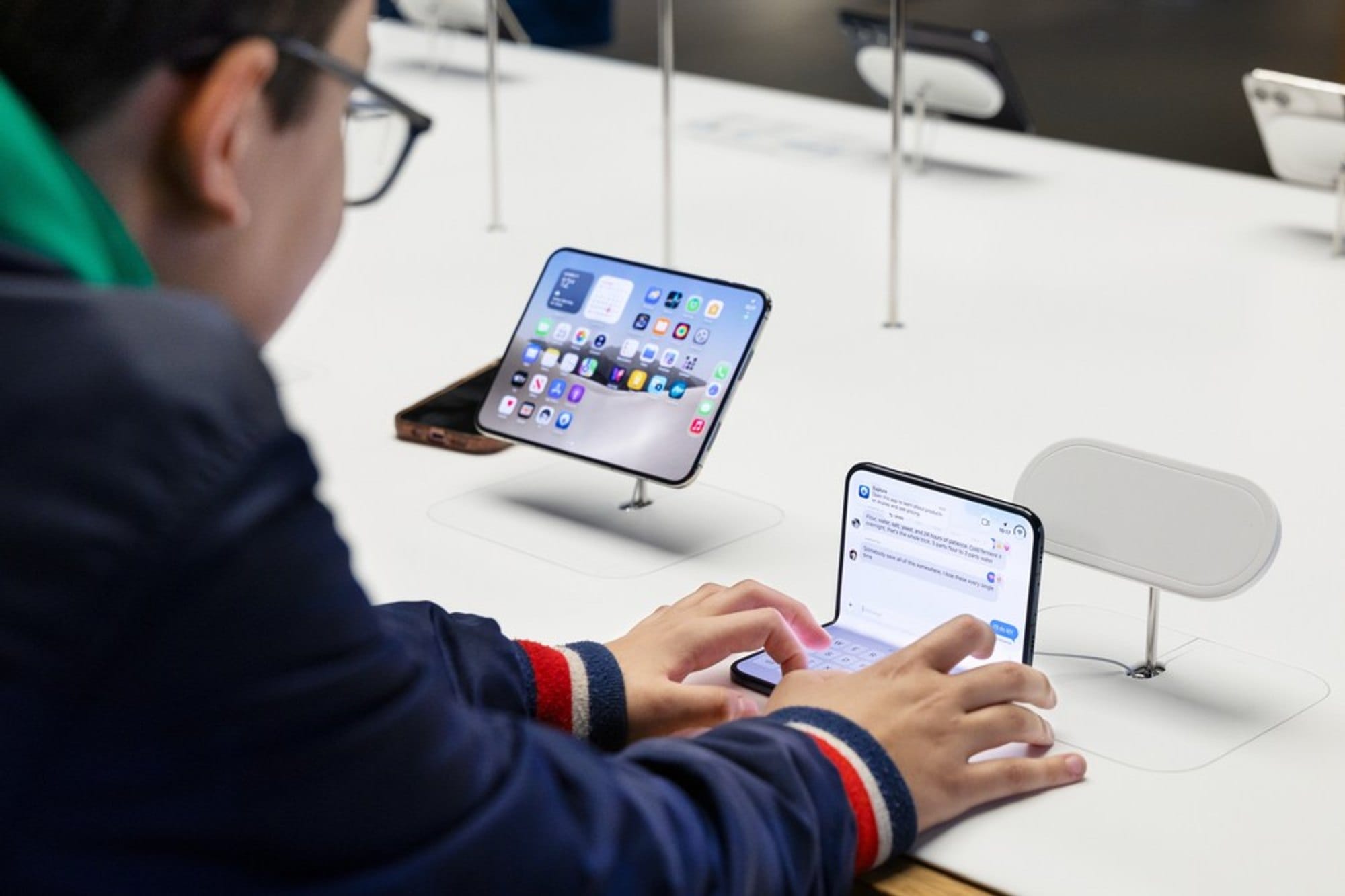 A customer types on an unfolded iPhone Duo at a display table
