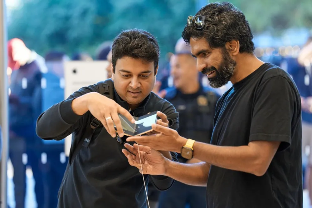 Two customers try the iPhone Duo hinge at an Apple Store display table