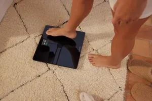 A person stepping onto a Withings smart scale on a rug