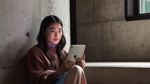 A person sitting by a window reading on the new iPad mini