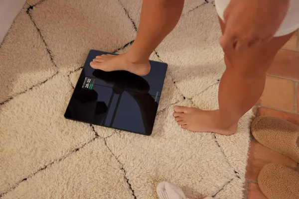 A person stepping onto a Withings smart scale on a rug